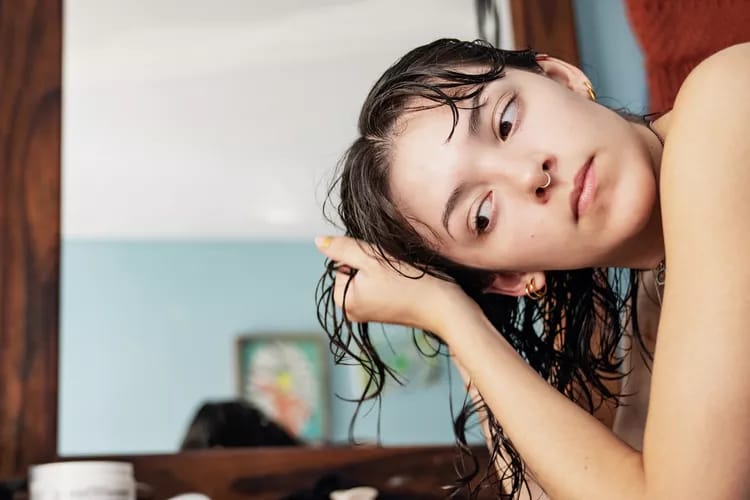 A girl washing her hair with apple cider vinegar rinse for shinier and healthier hair.