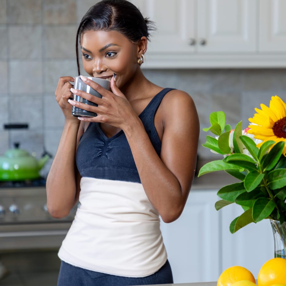 a woman applied castor oil pack on her abdomen to improve fertility improve circulation ans support reproductive health.