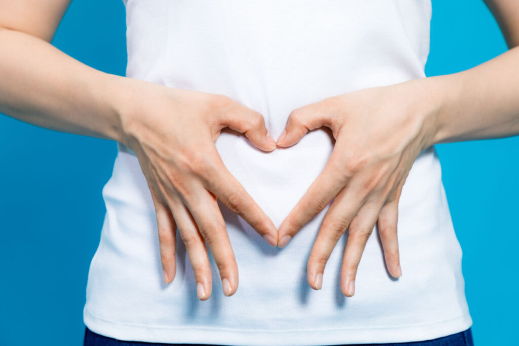 A person’s tummy with a glowing gut illustration, symbolizing improved digestion and gut health with apple cider vinegar.